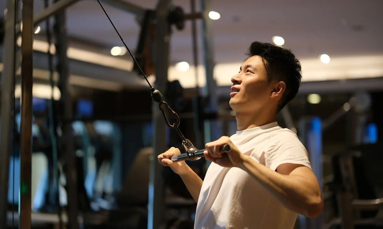 フィットネスジムでケーブルマシンを使ってトレーニングする男性